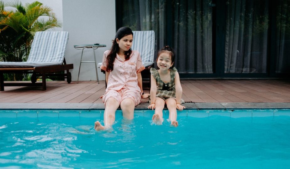 Duas crianças sentadas na beira da piscina