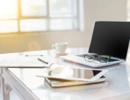 Notebook, caderno, óculos e tablet em cima de uma mesa